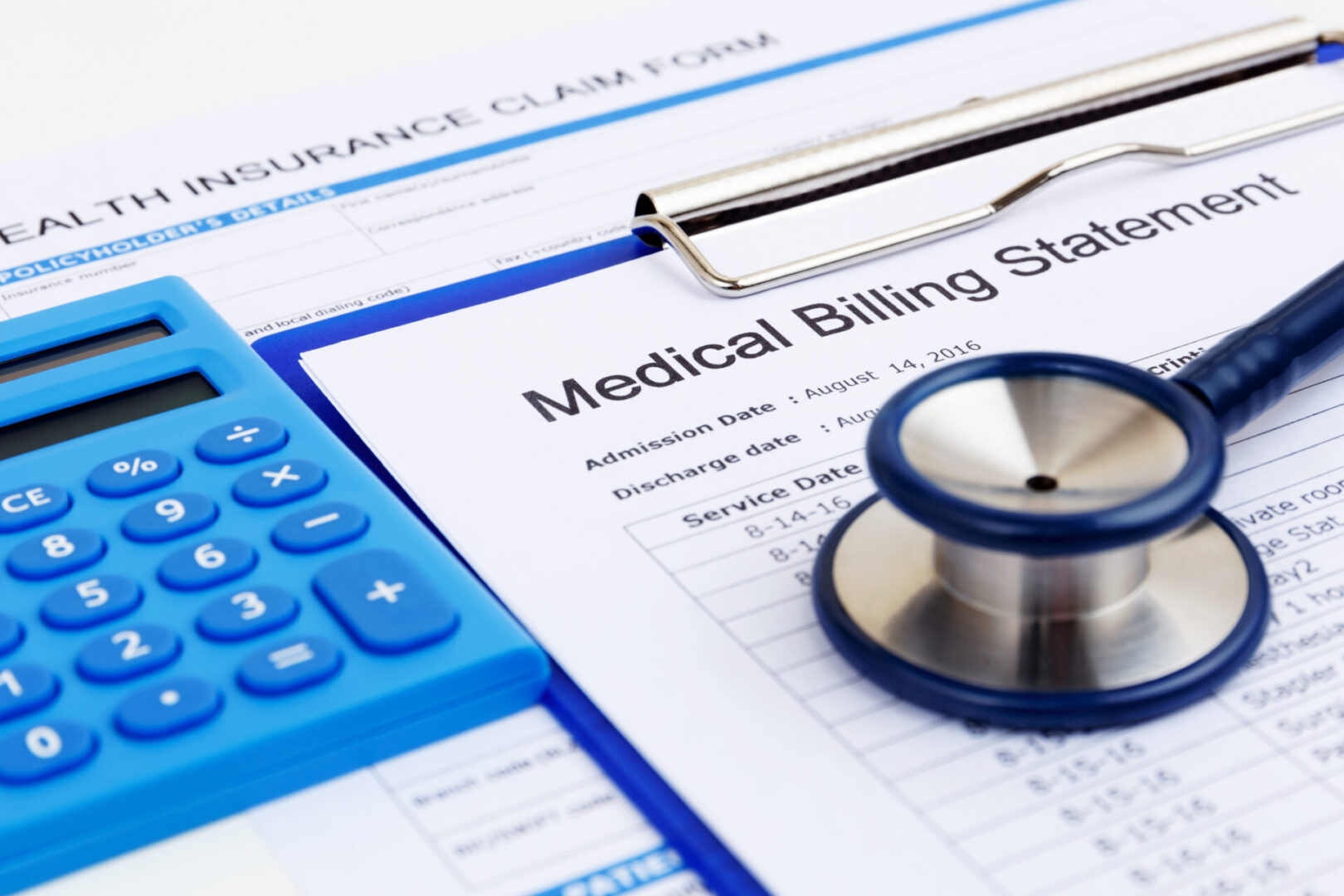 Medical bill and insurance form with calculator A medical billing statement is accompanied by a stethoscope and blue calculator atop a health insurance claim form, all neatly organized on a clipboard, illustrating the efficiency of modern medical billing software.